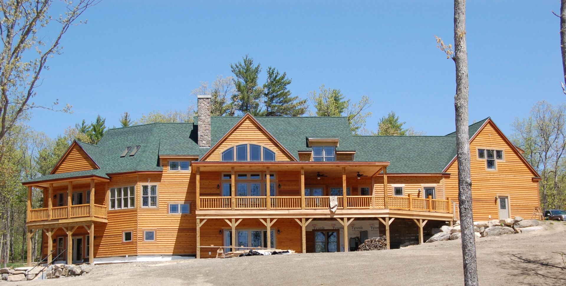 A large wooden house with green roof and blue sky