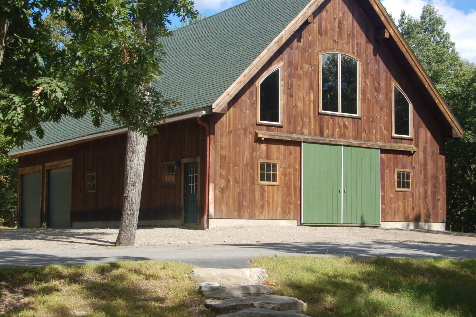 A barn with green doors and windows in the middle of it.