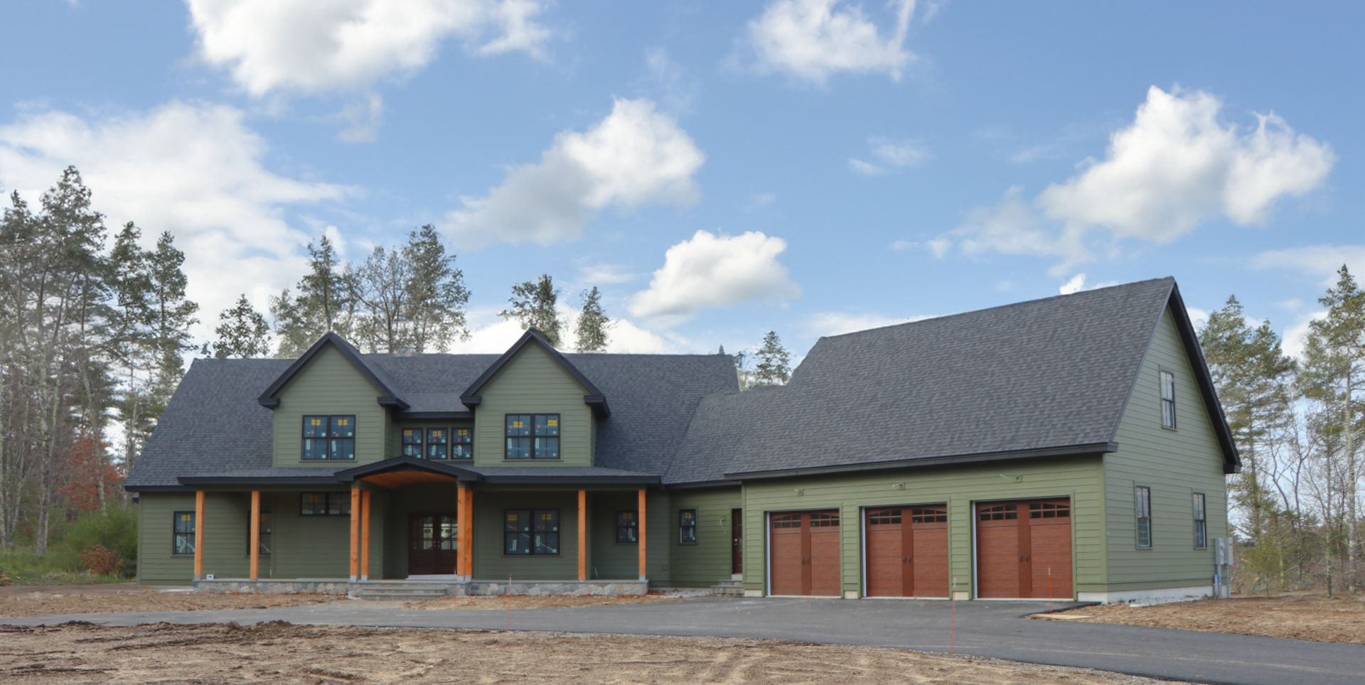 A large green house with three garage doors.